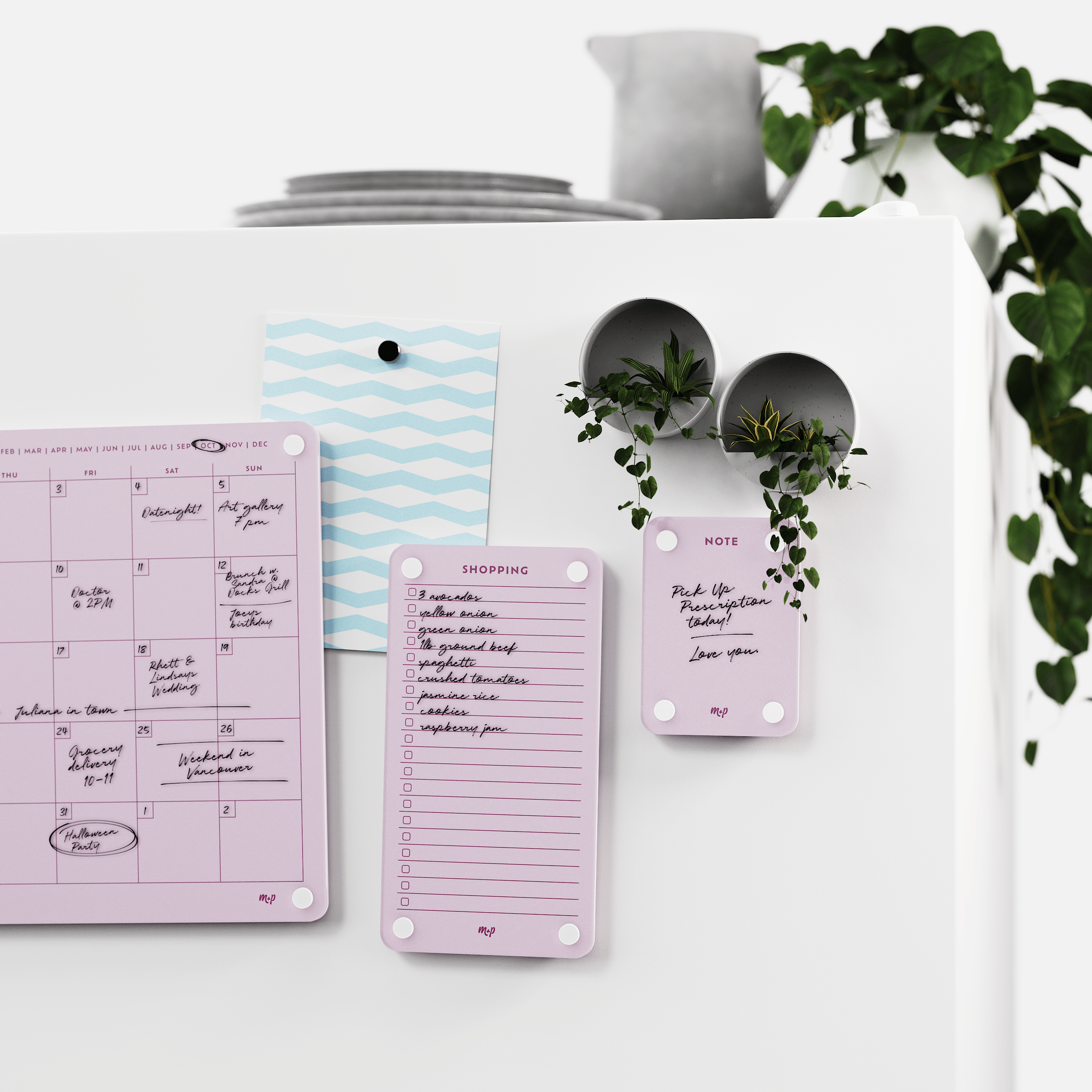 Ballet pink calendar, shopping list and note board on a white wall beside two magnetic planters